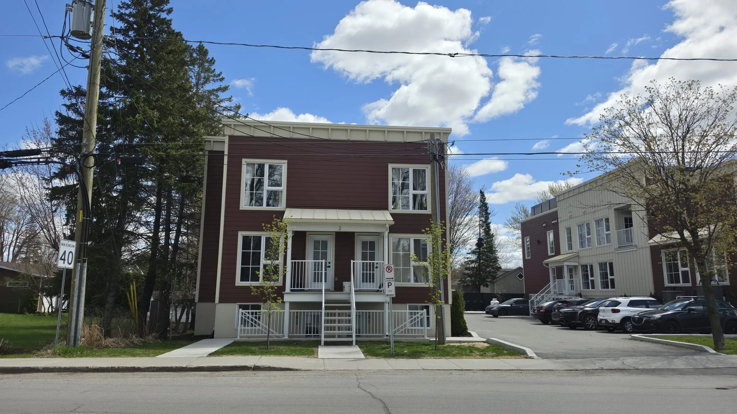 Façade d'un bâtiment de logements : parement rouge à panneaux verticaux, balcons et entrées individuelles