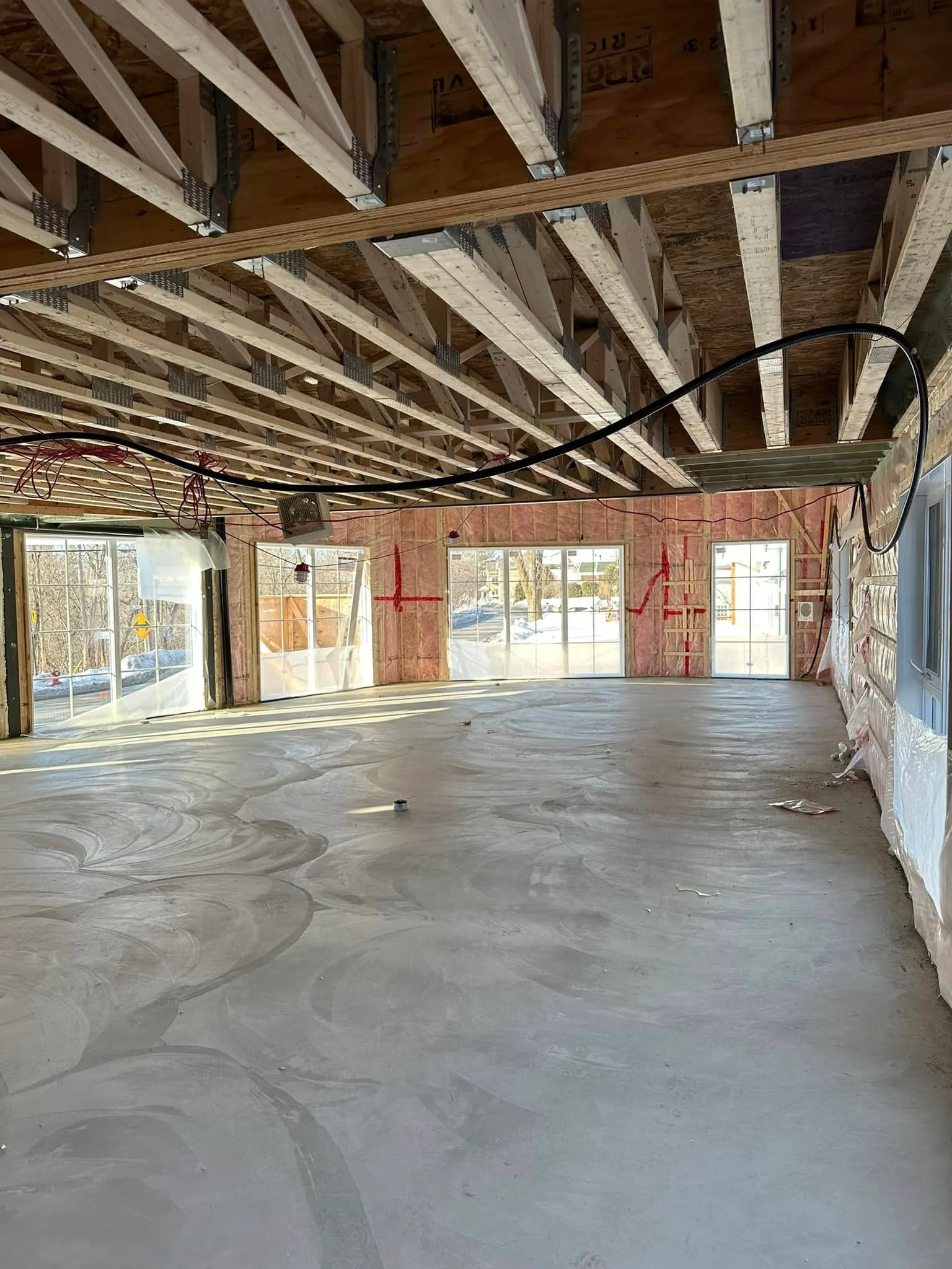 Le grand volume du futur gym en chantier : poutres de bois apparentes, dalle de béton et larges ouvertures