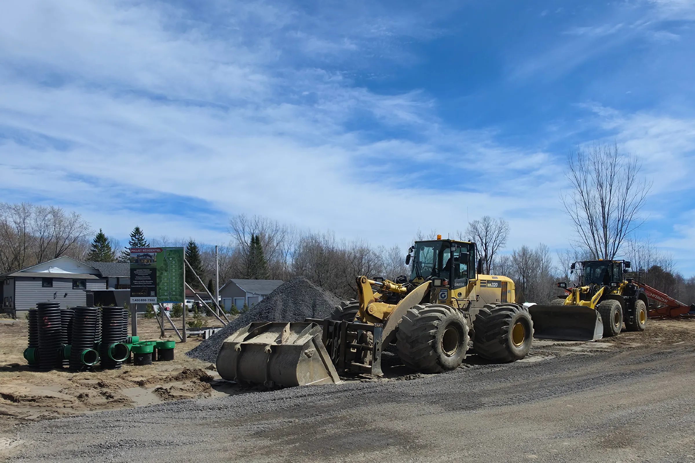 Chargeuses sur pneus et infrastructures de drainage en cours d'installation sur la nouvelle rue de viabilisation au Chemin 15
