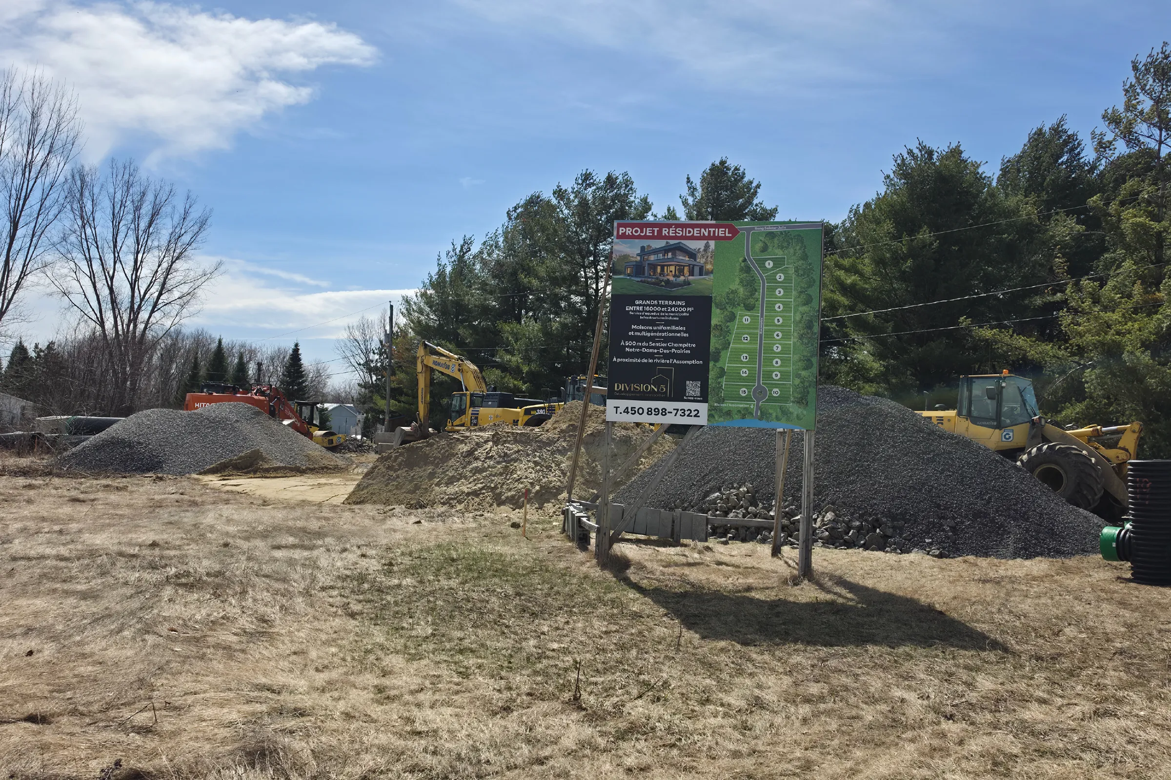 Panneau du projet résidentiel Division 5 installé sur le site, machinerie et matériaux de viabilisation en arrière-plan
