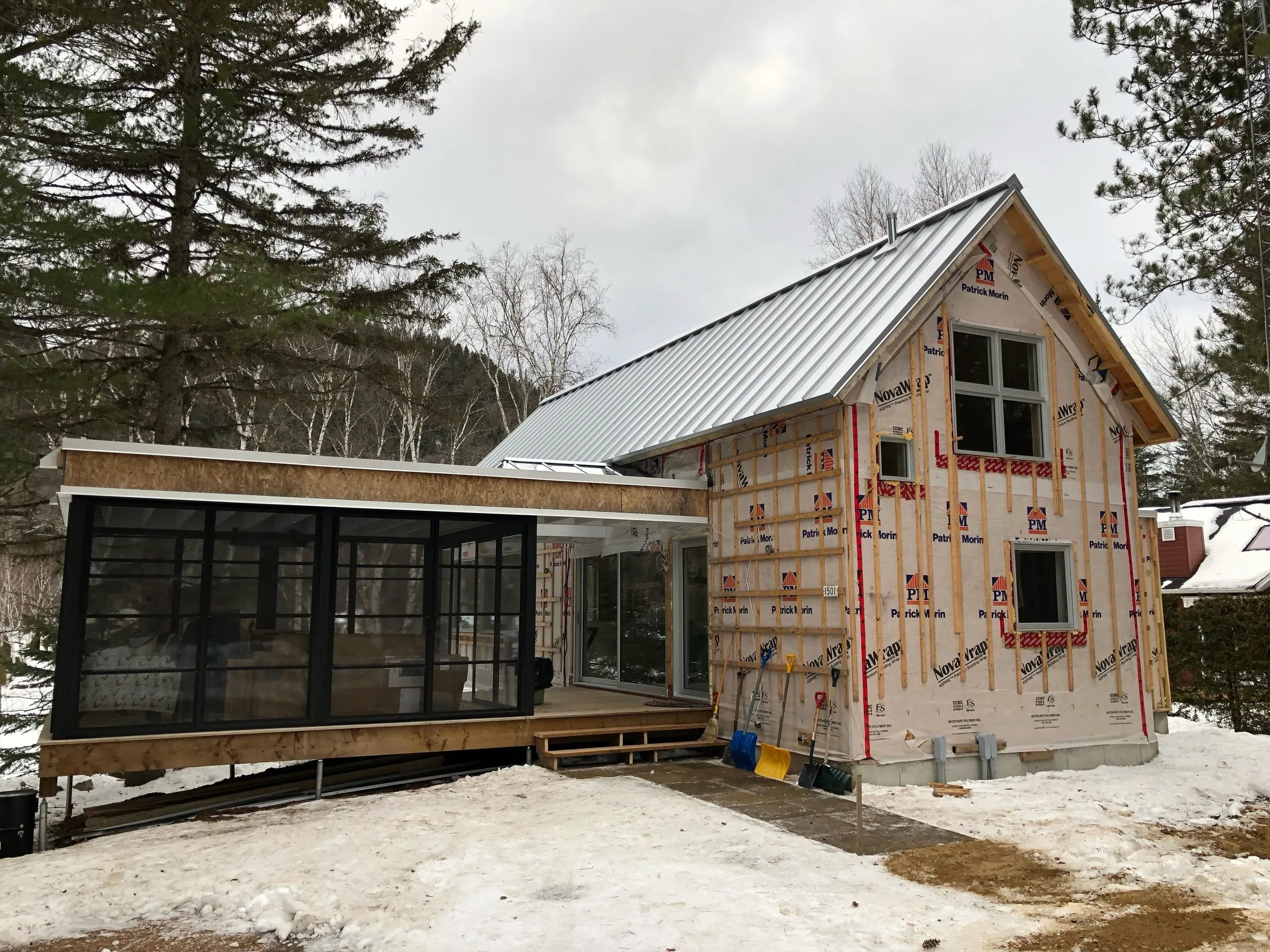 Solarium vitré en aluminium noir accolé au chalet, toiture métallique posée