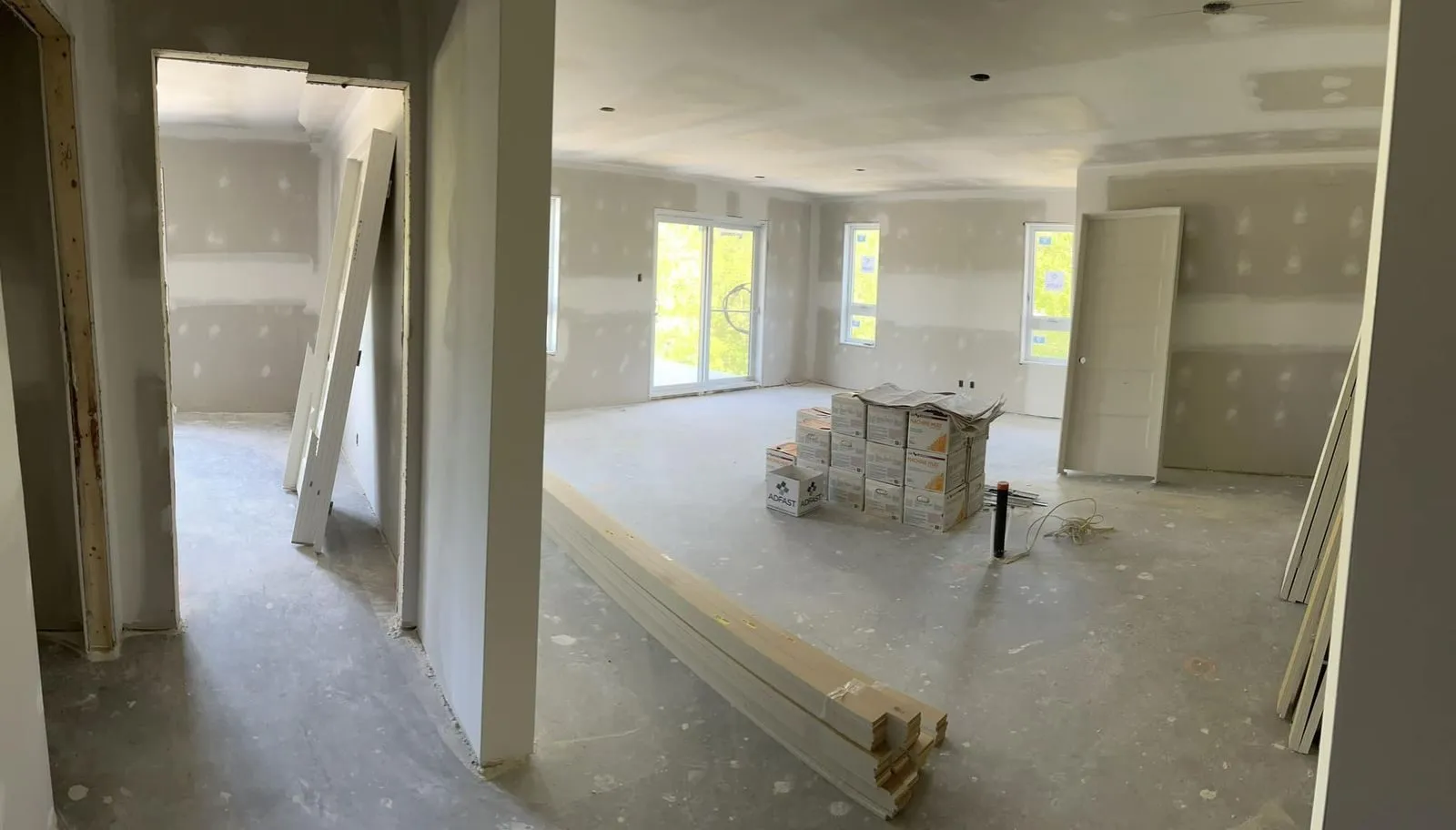 Aire de vie ouverte d'un logement, porte-patio et fenêtres installés, cloisons de gypse en place
