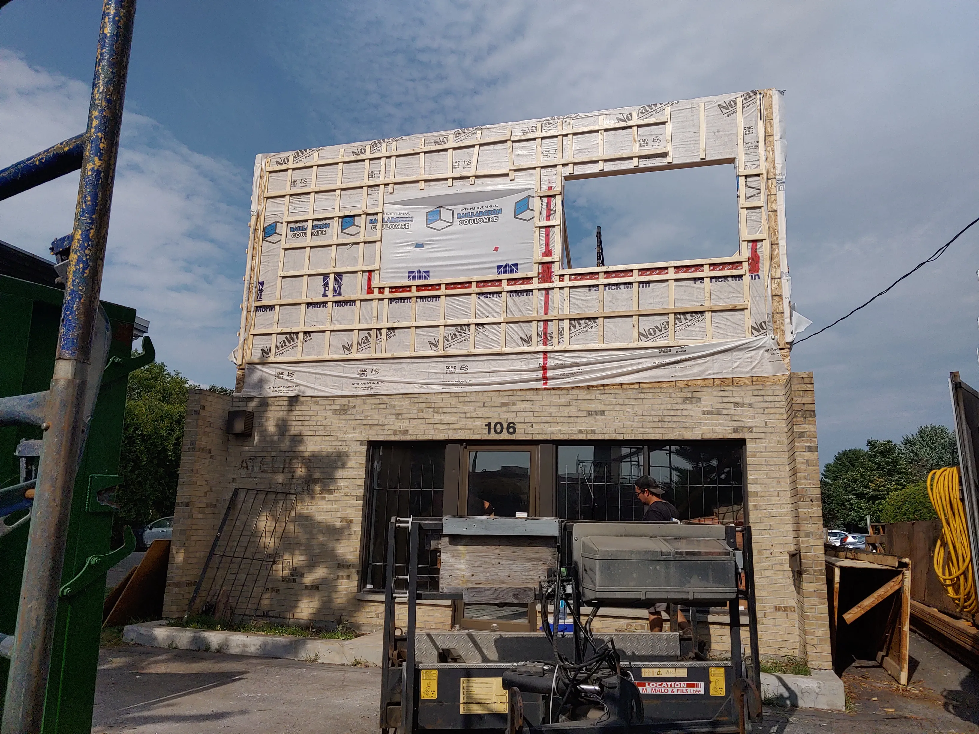 La base de maçonnerie existante et la nouvelle structure en cours de montage, vue de la rue