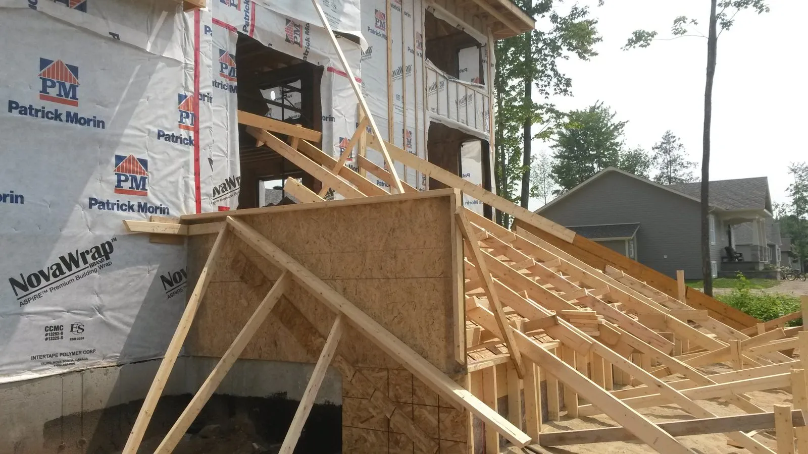 Coffrage de bois de l'escalier de béton devant la façade encore sous membrane pare-air