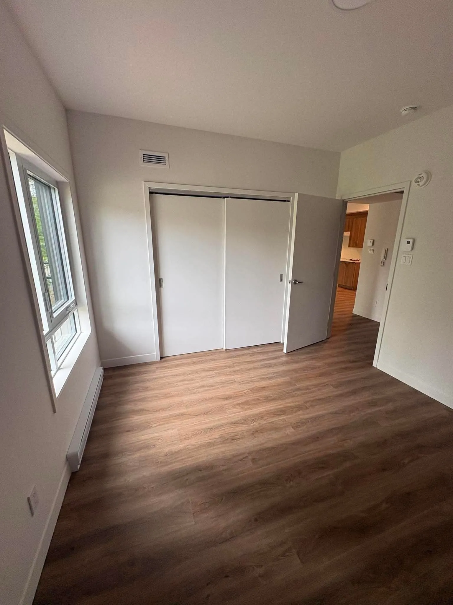 Chambre d'un logement avec fenêtre et garde-robe à portes coulissantes