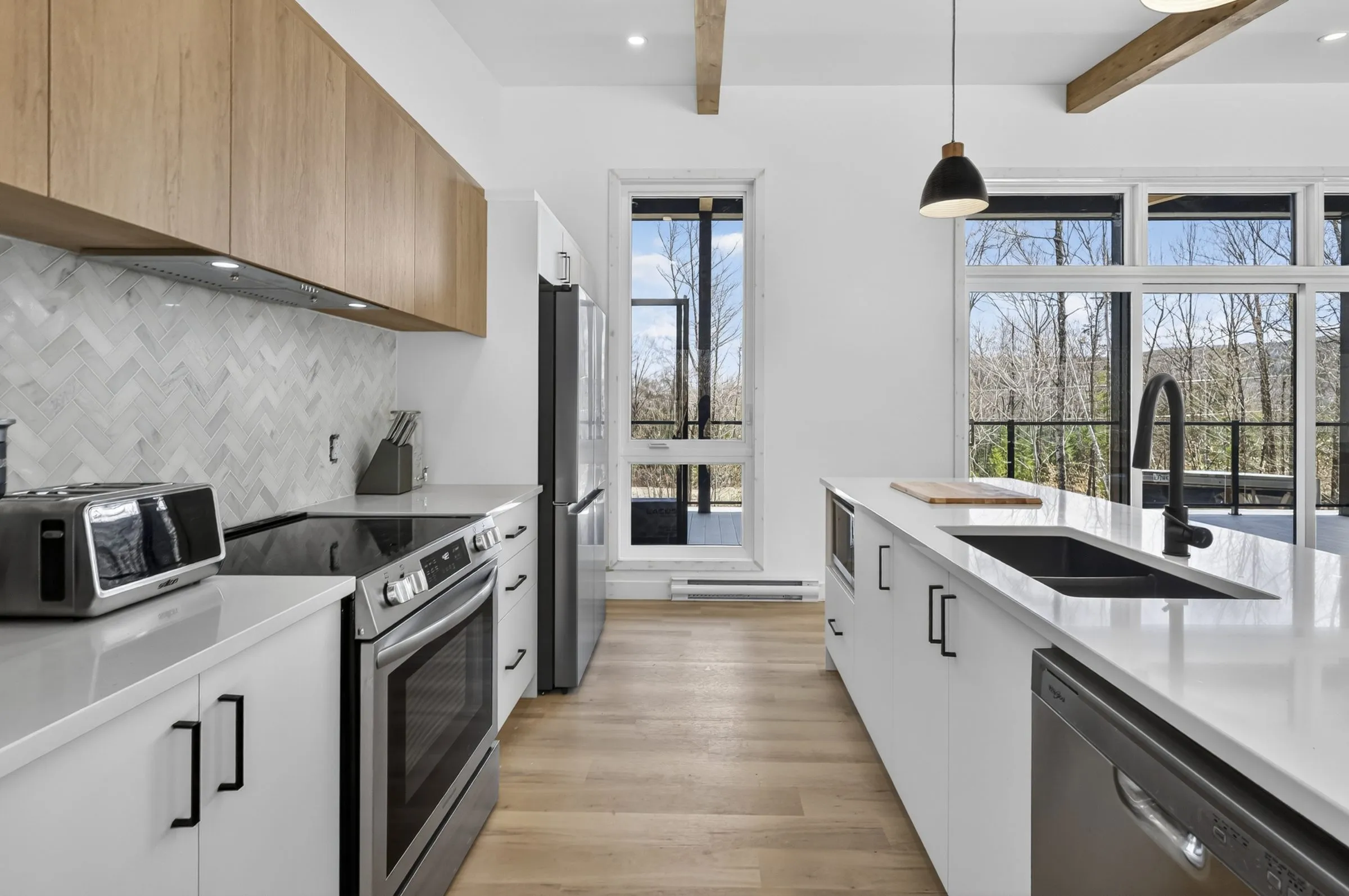 Cuisine avec comptoirs de quartz blanc, armoires de bois et dosseret à chevrons