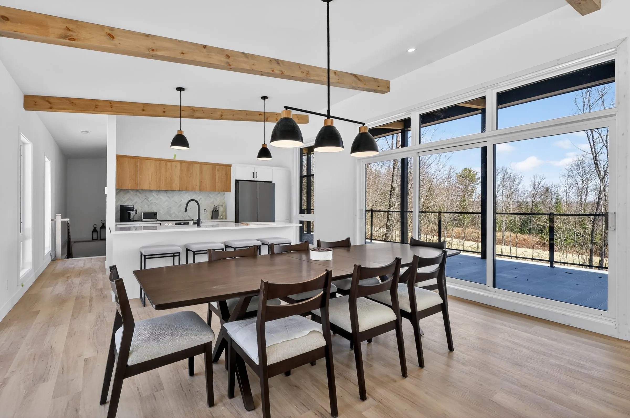 Salle à manger sous poutres de bois apparentes, ouverte sur la terrasse