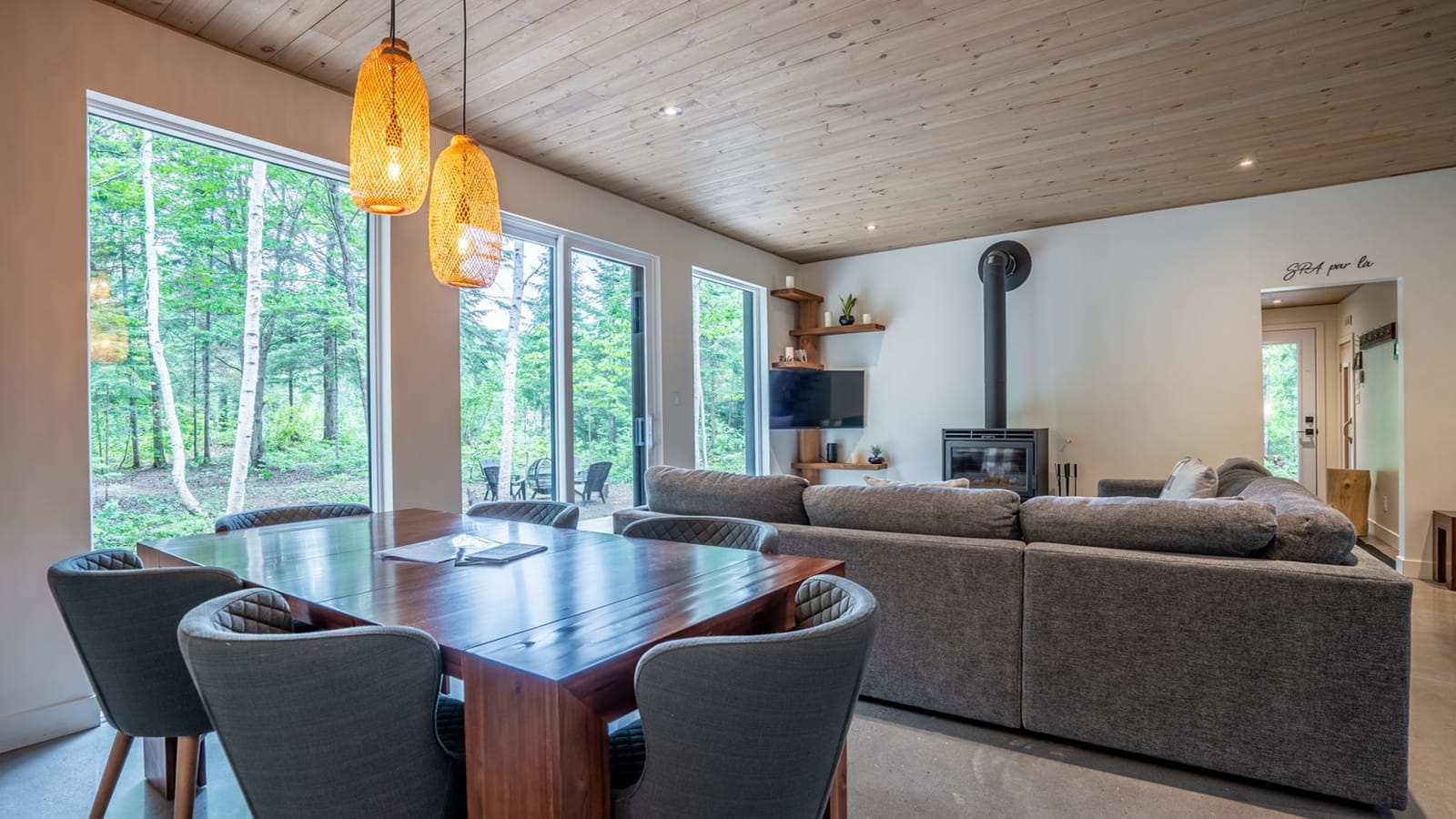 Salon-salle à manger du chalet LEED de Saint-Côme avec vue panoramique sur la forêt